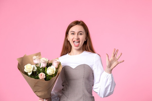 Vooraanzicht jonge vrouw met boeket van mooie rozen op roze