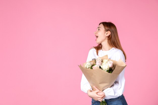 Vooraanzicht jonge vrouw met boeket van mooie rozen op roze