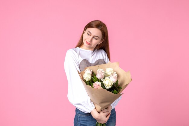 Vooraanzicht jonge vrouw met boeket van mooie rozen op roze