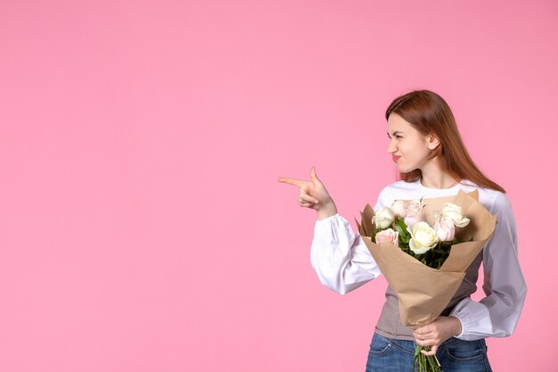 Vooraanzicht jonge vrouw met boeket van mooie rozen op roze