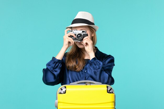 Vooraanzicht jonge vrouw met camera en het nemen van foto's op de blauwe achtergrond vrouw reis zee reizen reis vliegtuig