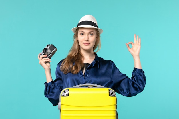 Vooraanzicht jonge vrouw met camera en lachend op de blauwe achtergrond vrouw reis reis vliegtuig zee