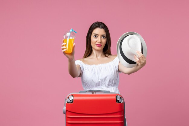 Vooraanzicht jonge vrouw met cocktail en hoed op vakantie op de roze muur hitte zomer kleur vakantie reis reis