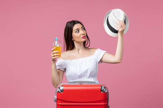Vooraanzicht jonge vrouw met cocktail en hoed op vakantie op de roze muur hitte zomer kleur vakantie reis reis