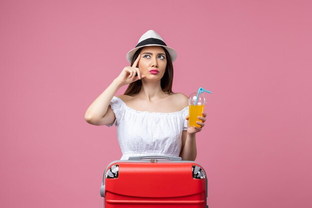 Vooraanzicht jonge vrouw met cocktail in zomervakantie op de roze muur vakantie warmte reis zomervakantie