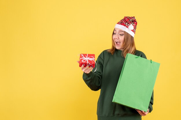 Vooraanzicht jonge vrouw met een klein cadeautje en boodschappenpakket