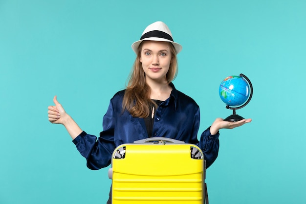 Vooraanzicht jonge vrouw met globe en voorbereiding op vakantie op blauwe achtergrond vliegtuig vrouwelijke vakantie reis reis