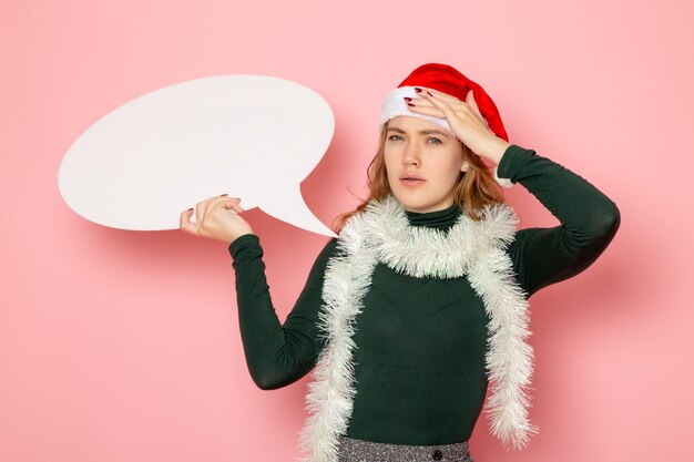 Vooraanzicht jonge vrouw met groot wit bord op roze muur model Kerstmis Nieuwjaar vakantie kleur emoties