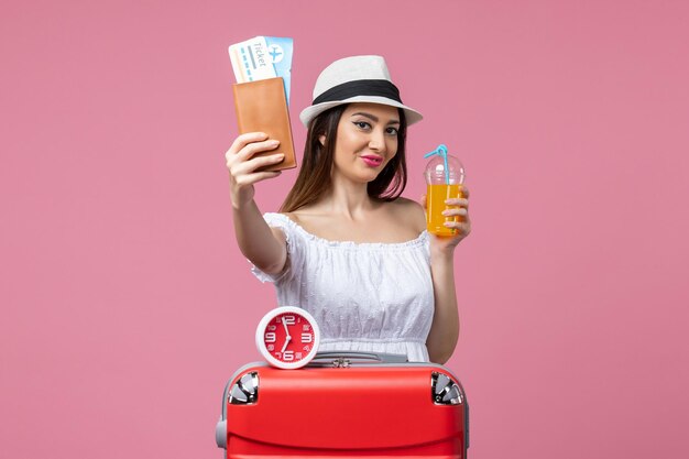 Vooraanzicht jonge vrouw met kaartjes en cocktail op vakantie op de roze muur reis vrouw vakantie reis zomerhitte