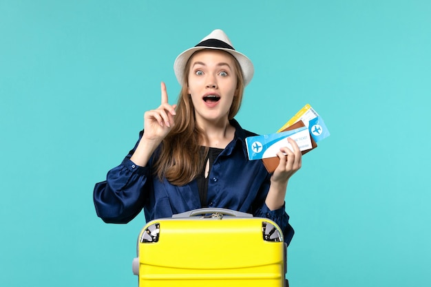 Vooraanzicht jonge vrouw met kaartjes en voorbereiding op vakantie op blauwe bureau zee reis reis vliegtuig vakantie
