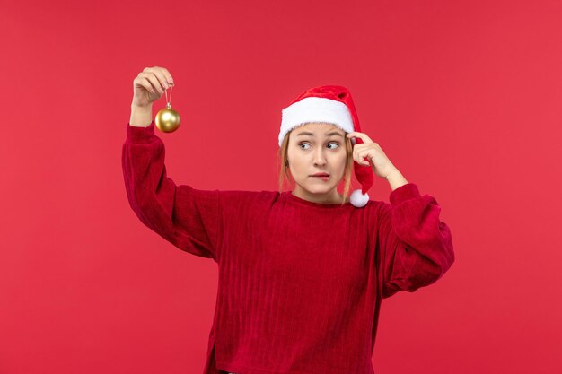 Vooraanzicht jonge vrouw met kerstbal speelgoed, rode kerstvakantie