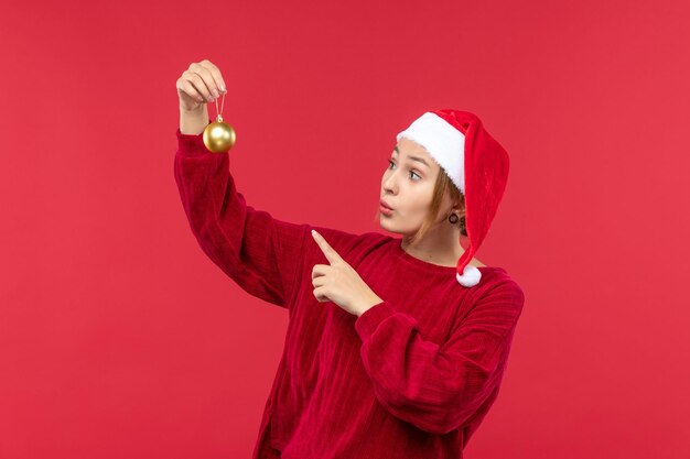 Vooraanzicht jonge vrouw met kerstspeelgoed, kerstvakantie rood