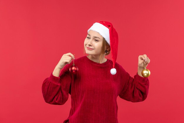 Vooraanzicht jonge vrouw met kerstspeelgoed op rode bureau kerstvakantie emoties