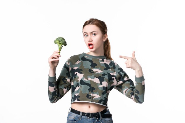 Vooraanzicht jonge vrouw met kleine broccoli op witte achtergrond maaltijd dieet salade schotel lichaam lunch voedsel gezondheid