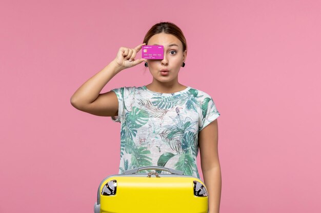 Vooraanzicht jonge vrouw met paarse bankkaart op vakantie op lichtroze muur zomerrust kleur reis vakantie vrouw