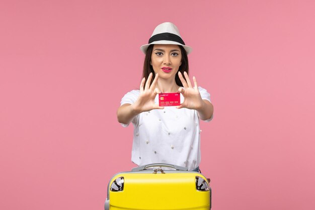 Vooraanzicht jonge vrouw met rode bankkaart op de roze muur zomerreis reis