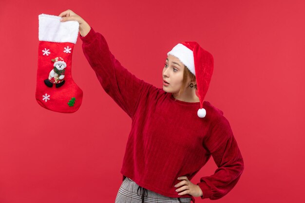 Vooraanzicht jonge vrouw met rode kerstsok op rode bureau kerstvakantie rood