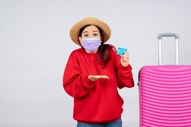 Vooraanzicht jonge vrouw met roze tas met bankkaart in masker op witte muur