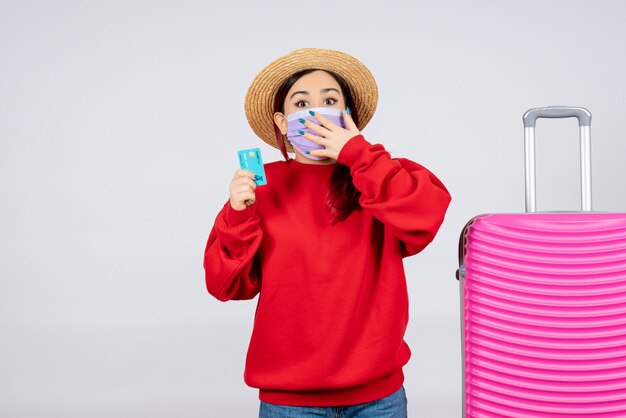 Vooraanzicht jonge vrouw met roze tas met bankkaart in masker op witte muur