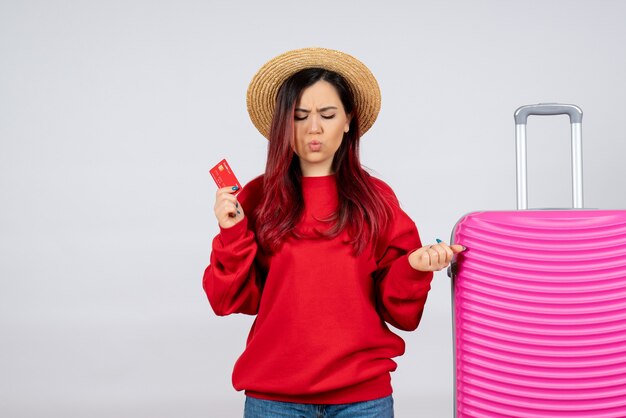 Vooraanzicht jonge vrouw met roze tas met rode bankkaart op witte muur