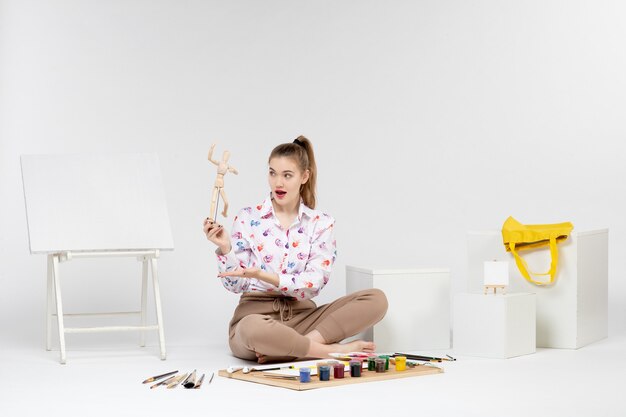 Vooraanzicht jonge vrouw met speelgoed menselijke figuur op witte achtergrond