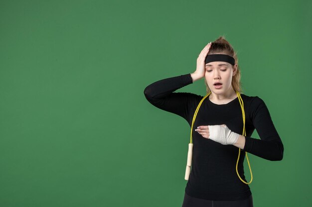 Vooraanzicht jonge vrouw met verband rond haar gewonde arm op groen