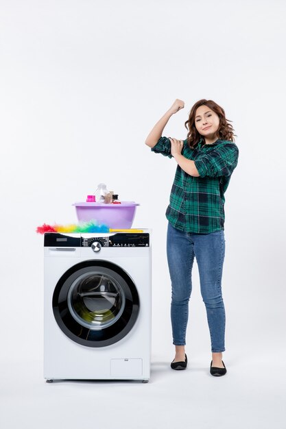 Vooraanzicht jonge vrouw met wasmachine en shampoo op witte muur