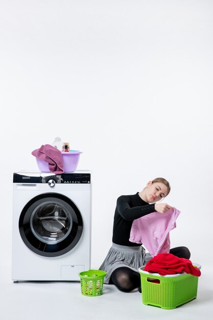 Vooraanzicht jonge vrouw met wasmachine en vuile kleren op witte muur