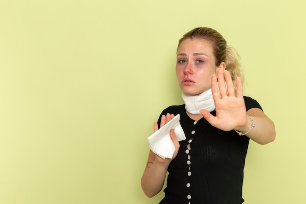 Gratis foto vooraanzicht jonge vrouw met witte handdoek om haar keel erg ziek en ziek voelen op de groene muur ziekte ziekte vrouwelijke kleur gezondheid