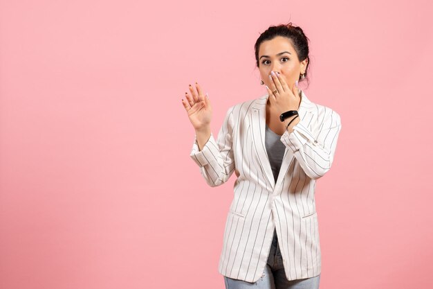 Vooraanzicht jonge vrouw met witte jas en verrast gezicht op roze achtergrond kleding dame emoties kleur mode vrouw