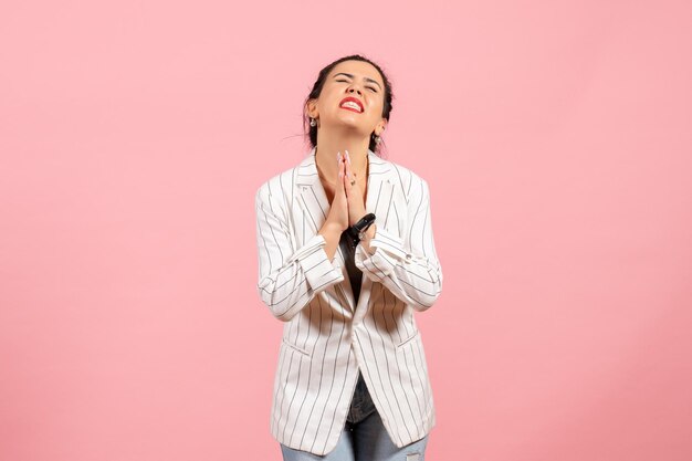 Vooraanzicht jonge vrouw met witte jas in bedelende pose op roze achtergrond dame emoties mode gevoel kleur vrouw