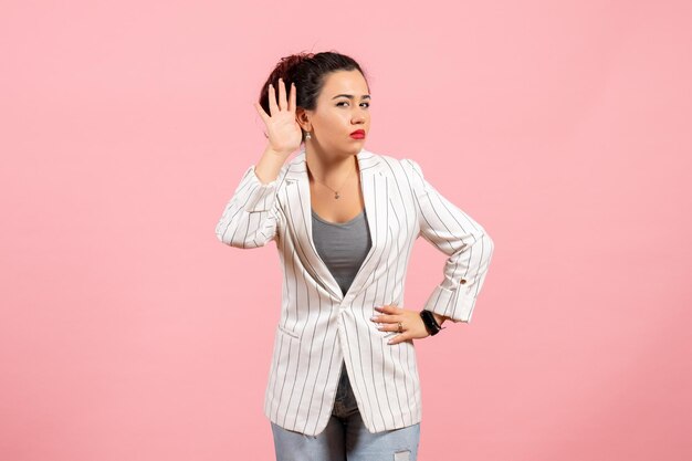 Vooraanzicht jonge vrouw met witte jas wijzend op roze achtergrond dame emoties mode gevoel kleur vrouw