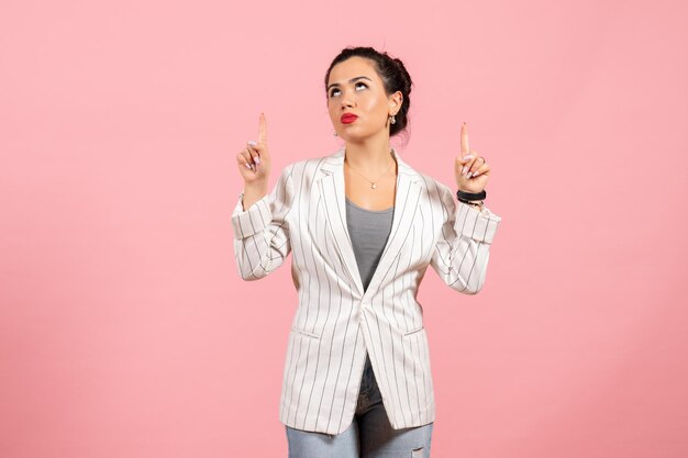 Vooraanzicht jonge vrouw met witte jas wijzend op roze achtergrond dame emoties mode kleur gevoel vrouw