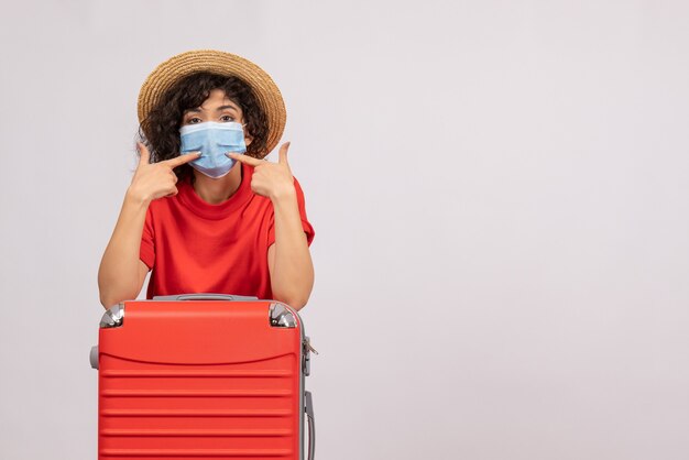 Vooraanzicht jonge vrouw met zak in masker op een witte achtergrond zon kleur covid- pandemische vakantiereis toeristenvirus