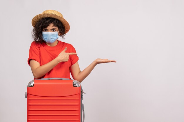 Vooraanzicht jonge vrouw met zak in masker op witte achtergrond kleur virus covid- pandemische vakantiereis zon