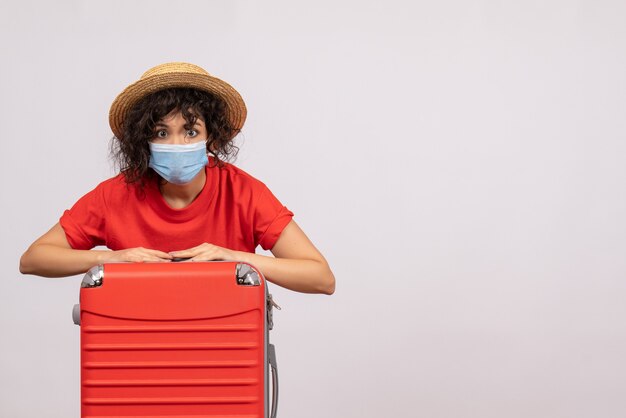 Vooraanzicht jonge vrouw met zak in masker op witte achtergrondkleur covid-pandemische zon virus reis toeristische vakantie