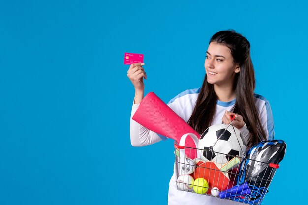 Vooraanzicht jonge vrouw na sport winkelen met creditcard op blauwe muur