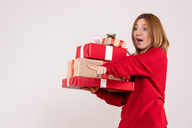 Vooraanzicht jonge vrouw staande met cadeautjes in haar handen