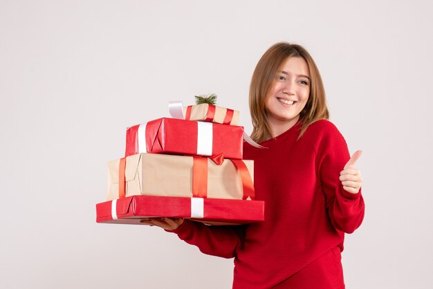 Vooraanzicht jonge vrouw staande met cadeautjes in haar handen