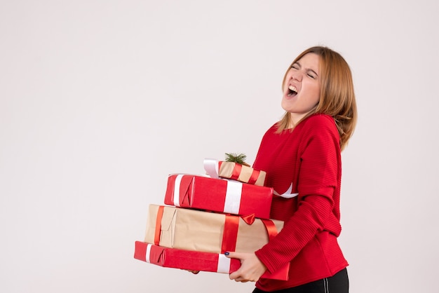 Vooraanzicht jonge vrouw staande met cadeautjes in haar handen