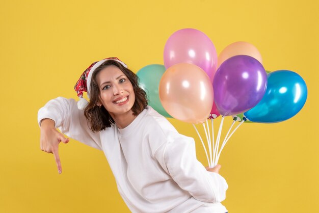 Vooraanzicht jonge vrouw verbergt kleurrijke ballonnen Nieuwjaar kerst kleur vakantie vrouw emotie