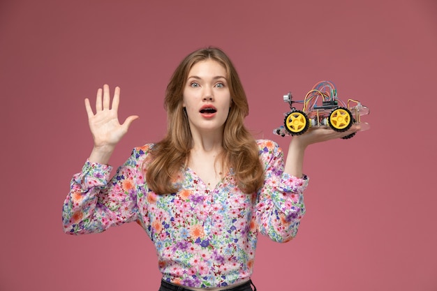 Gratis foto vooraanzicht jonge vrouw verrast door vreemd speelgoed auto-ontwerp