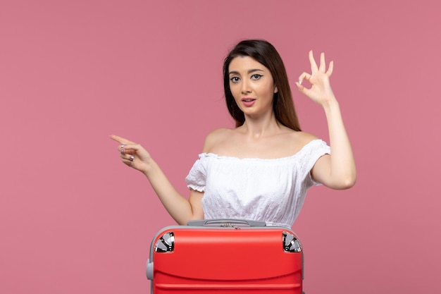 Vooraanzicht jonge vrouw voorbereiding op vakantie met haar rode tas op de reis van de roze achtergrond in het buitenland reizen zeereis reis
