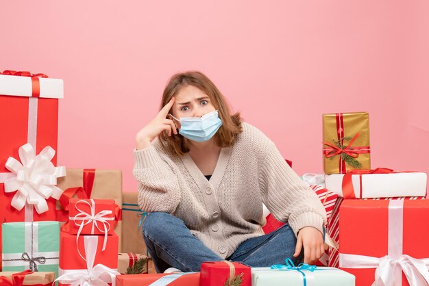 Vooraanzicht jonge vrouw zitten rond kerstcadeautjes in masker