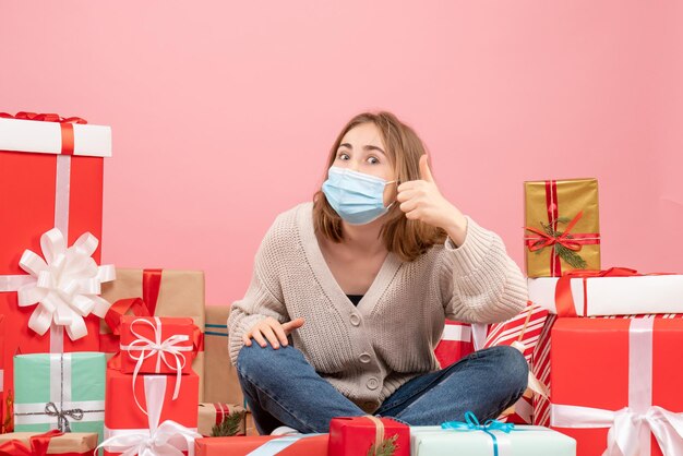 Vooraanzicht jonge vrouw zitten rond kerstcadeautjes in masker