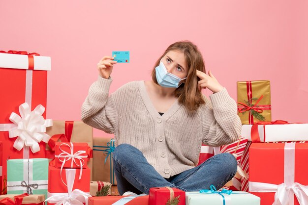 Vooraanzicht jonge vrouw zitten rond kerstcadeautjes in masker