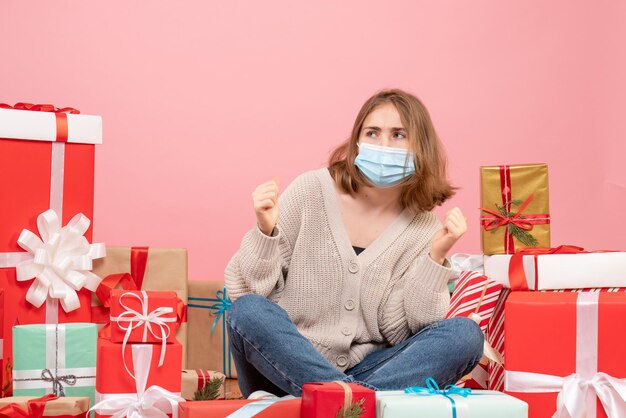 Vooraanzicht jonge vrouw zitten rond kerstcadeautjes in masker