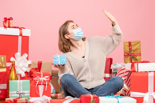 Vooraanzicht jonge vrouw zitten rond kerstcadeautjes in steriel masker