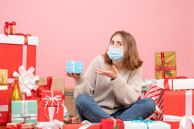 Vooraanzicht jonge vrouw zitten rond kerstcadeautjes in steriel masker