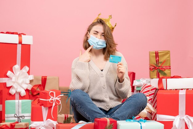 Vooraanzicht jonge vrouw zitten rond kerstcadeautjes in steriel masker